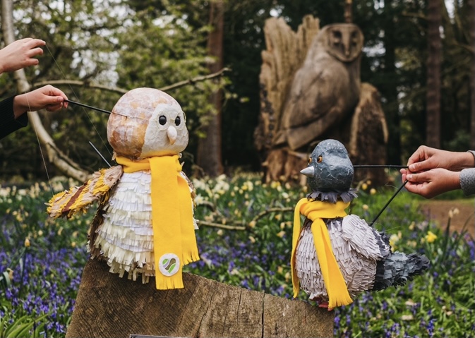Pidge the pigeon puppet with bright coloured yellow scarf amongst flowers from Leighton Buzzard Bee Local Magazine local news