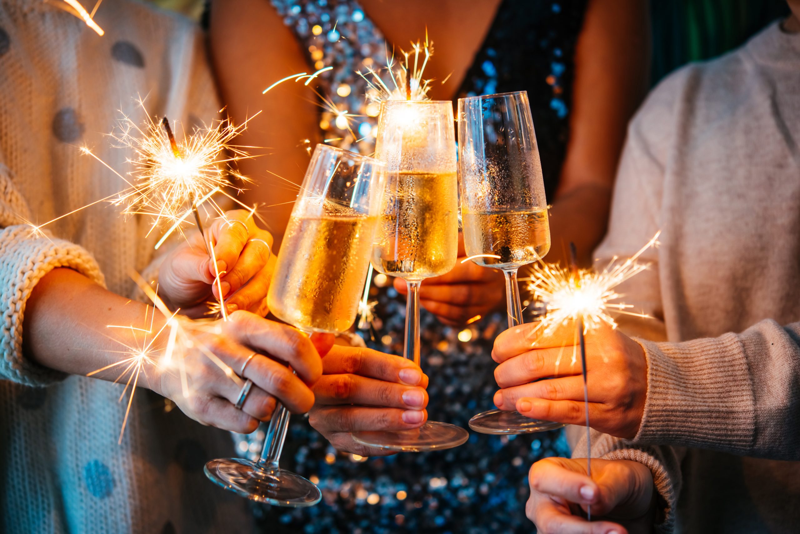 FRIENDS HOLDING GLASSES OF CHAMPAGNE AND SPARKLERS CELEBRATE NEW YEARS EVE IN lEIGHTON BUZZARD